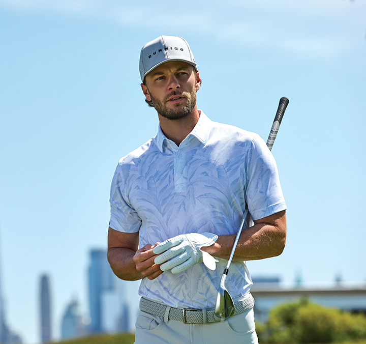 A man stands on a golf course in a COOLMAX® fabric polo shirt from Dunning.